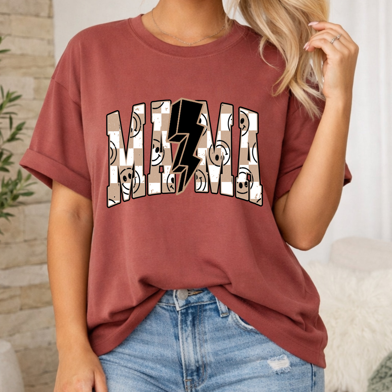 Person wearing a maroon t-shirt with graphic design and ripped jeans in a casual setting.